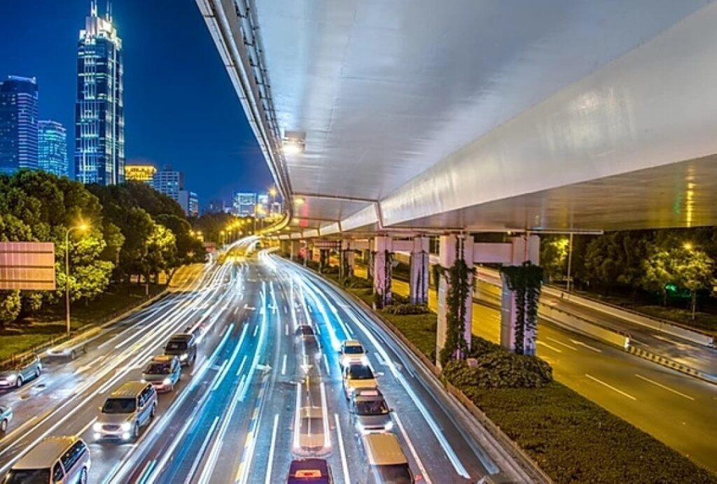 Foto de uma avenida com carros passando e iluminação azul entre as pistas