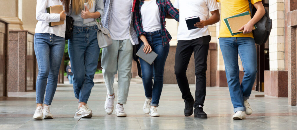 Imagem mostra as pernas de um grupo de jovens grupo de jovens caminhando em um corredor de escola
